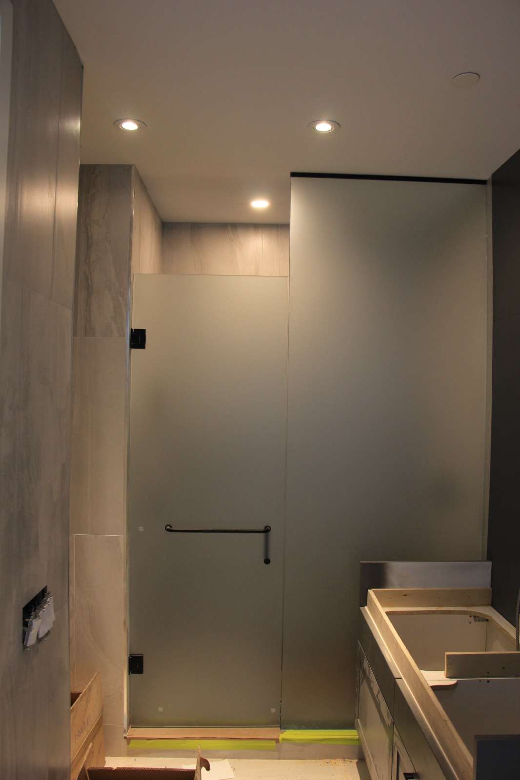 Frameless shower panel and door installed at a tub-and-shower alcove