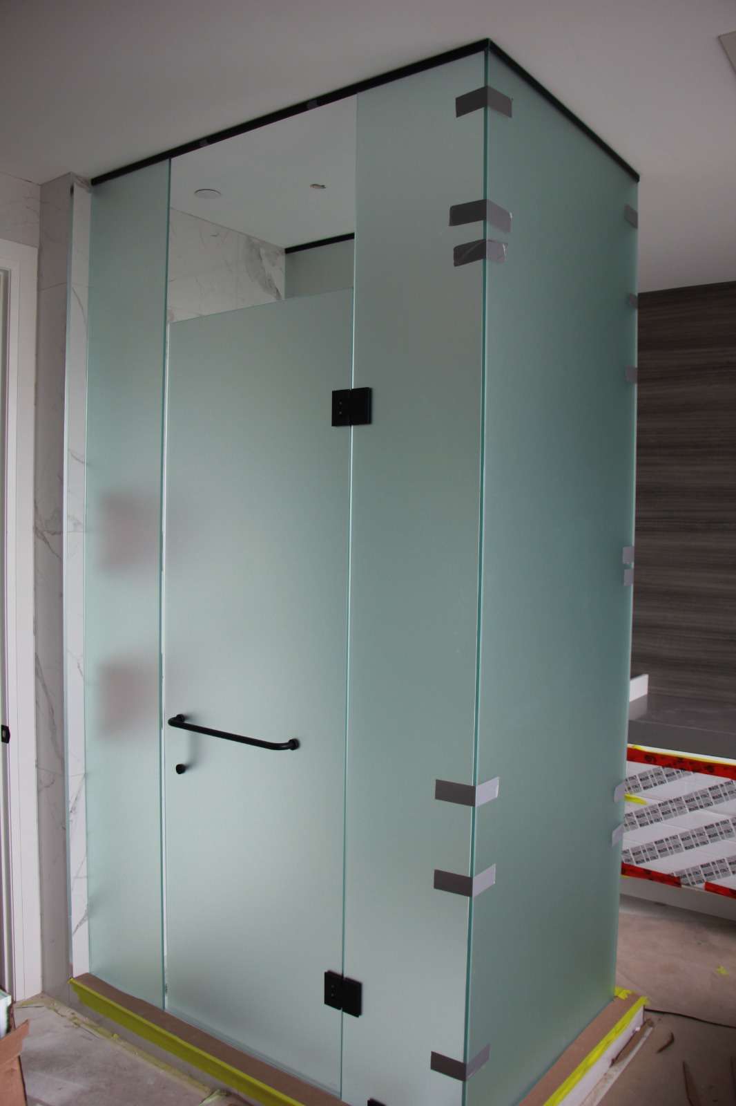 Frosted-glass shower enclosure with black hinges and handle on two walls