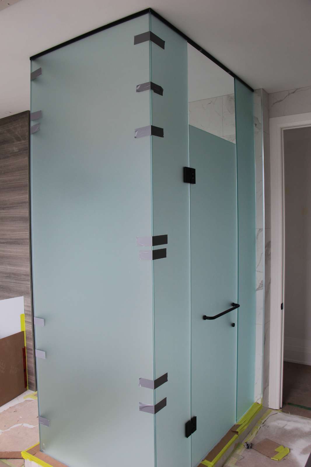 Frosted-glass shower enclosure with a hinged door, seen from the bathroom doorway
