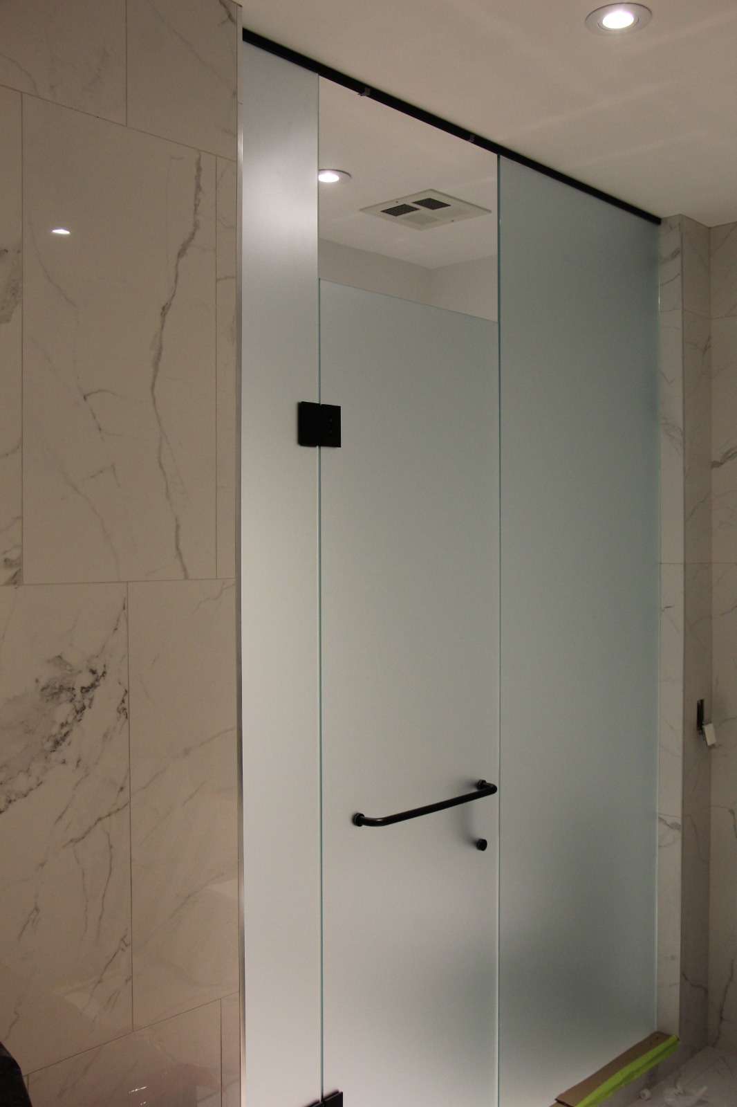 Frosted-glass shower door in a white marble surround