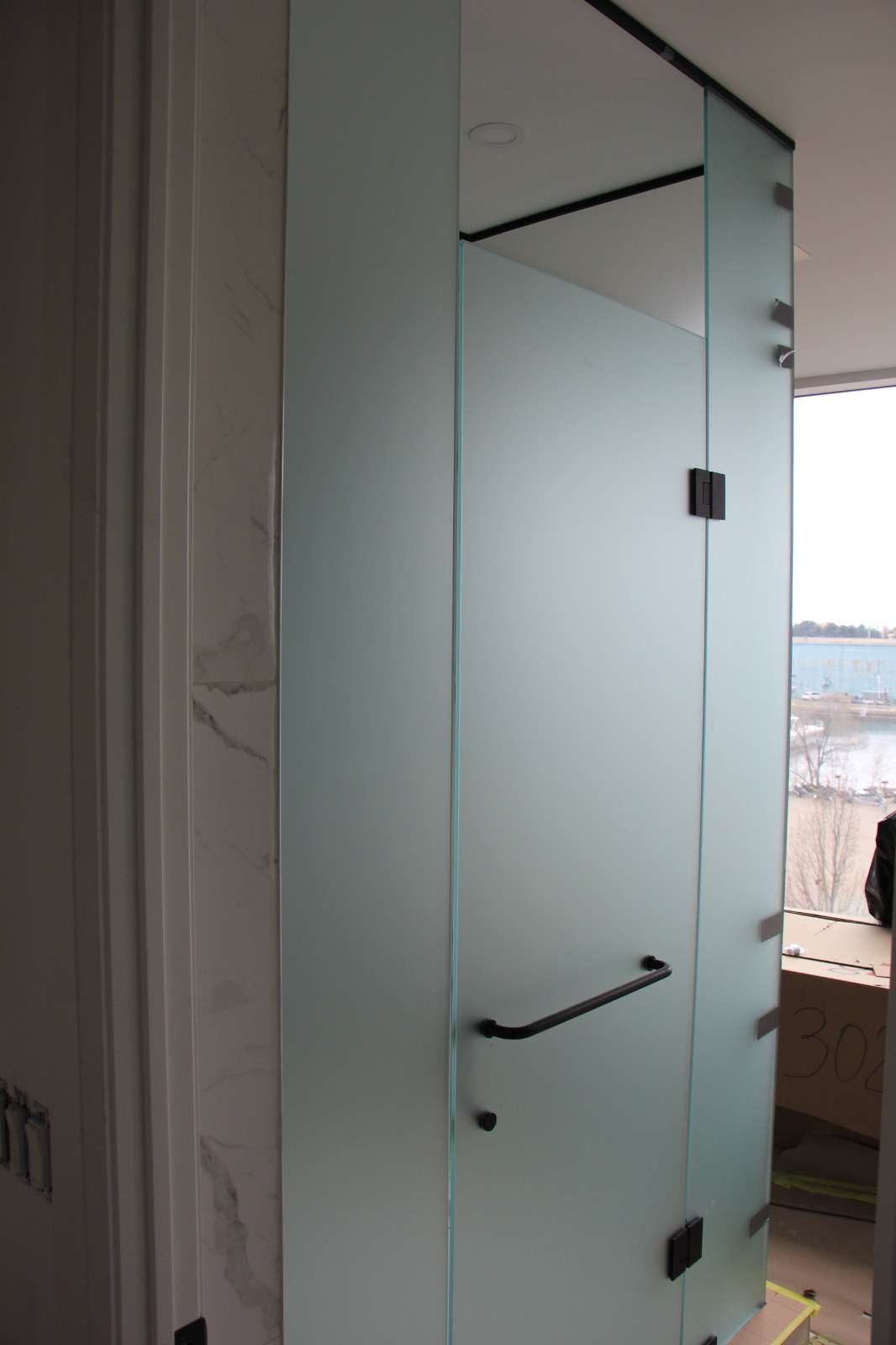 Frosted-glass shower enclosure beside a window