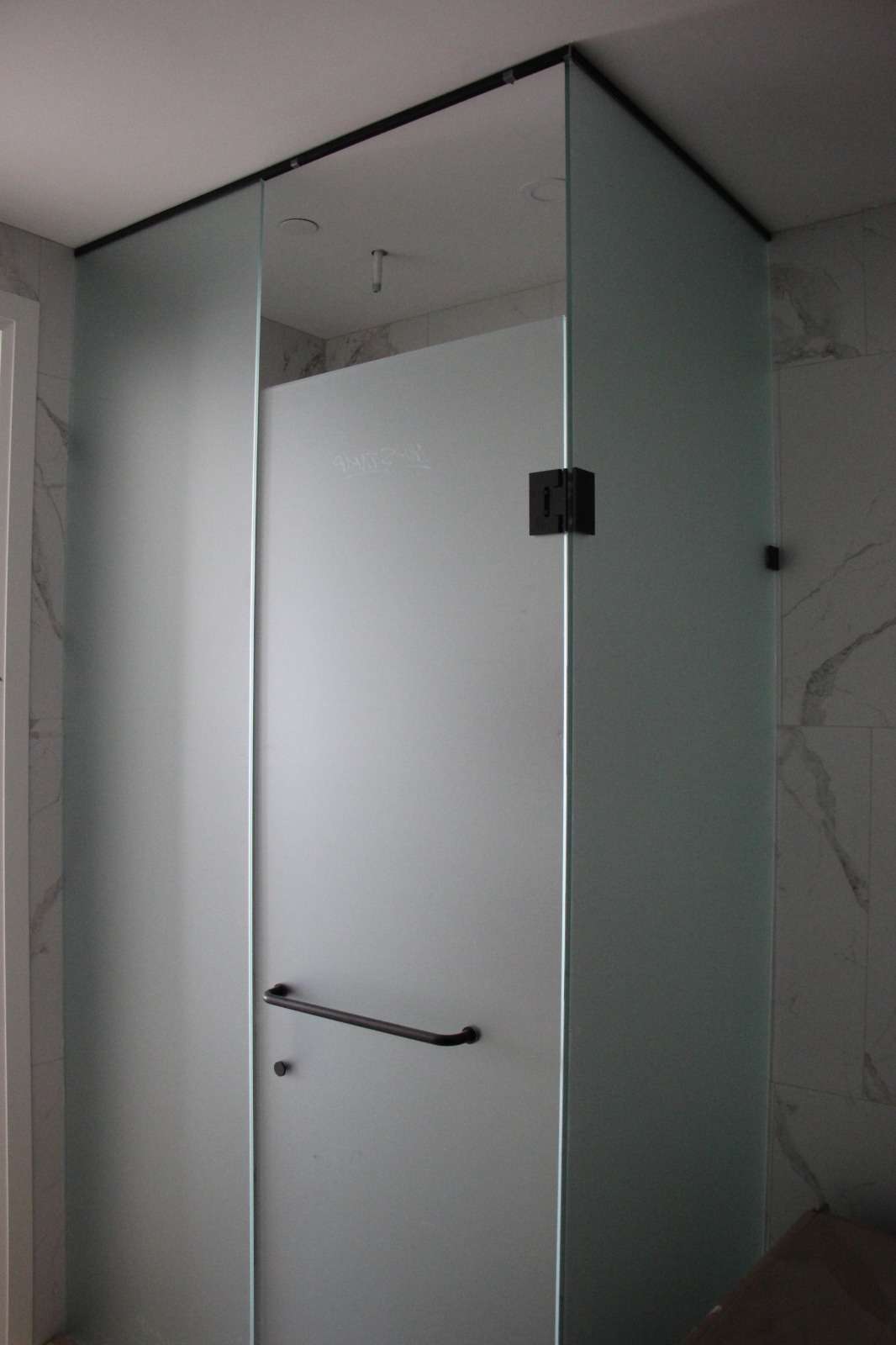 Corner frosted-glass shower enclosure with black hardware